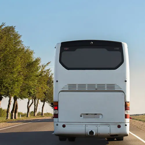 A white bus driving down a road.