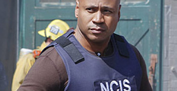 A man in a ncis vest standing in front of a building.