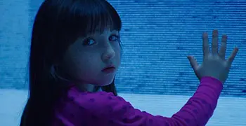 A young girl with her hand out in front of a blue screen.