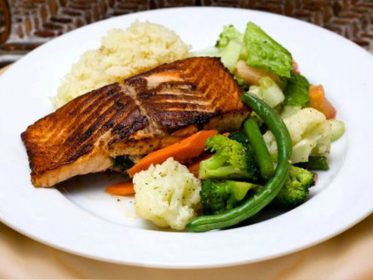 A plate of salmon and vegetables on a table.