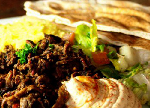 A plate with meat, rice and pita bread.