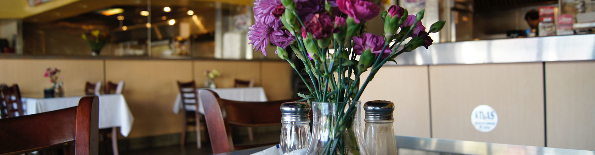 Purple flowers in a vase on a table in a restaurant.
