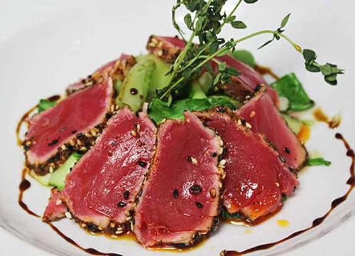 A plate of tuna and greens on a white plate.
