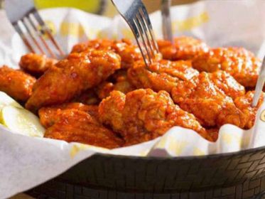 Chicken wings in a bowl with forks.