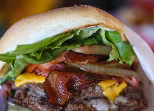 A burger with bacon, lettuce and tomatoes.
