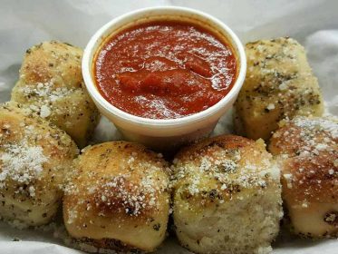 A tray of bread rolls with sauce and dipping sauce.
