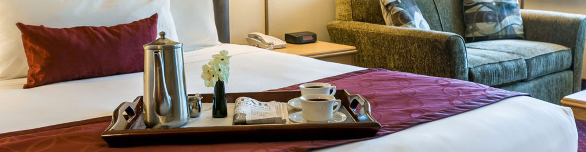 A bed in a hotel room with a tray.