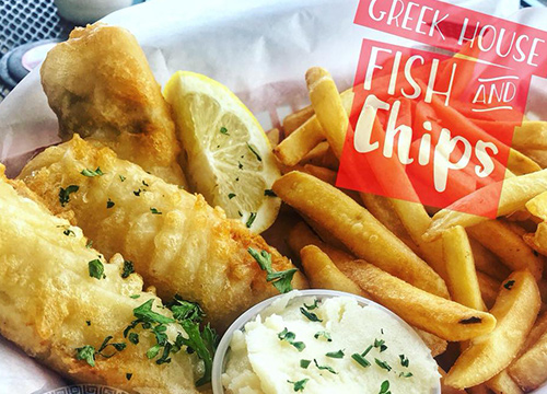 A plate of fish and chips with lemon wedges.