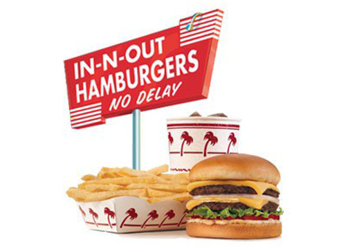 A hamburger, fries and a sign with the words in out hamburgers no delay''.