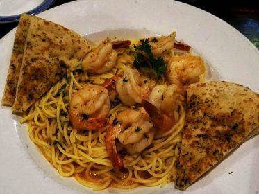 A plate of spaghetti and shrimp on a table.