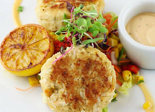 Crab cakes on a white plate with a sauce.