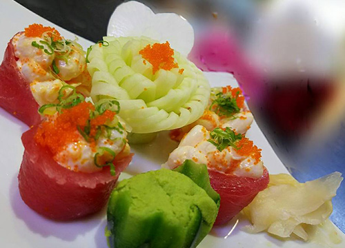 A white plate with sushi and vegetables on it.