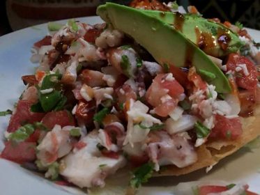 A tostada filled with seafood and avocado.