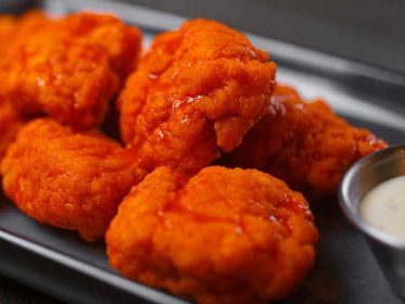 A plate of buffalo wings with dipping sauce.